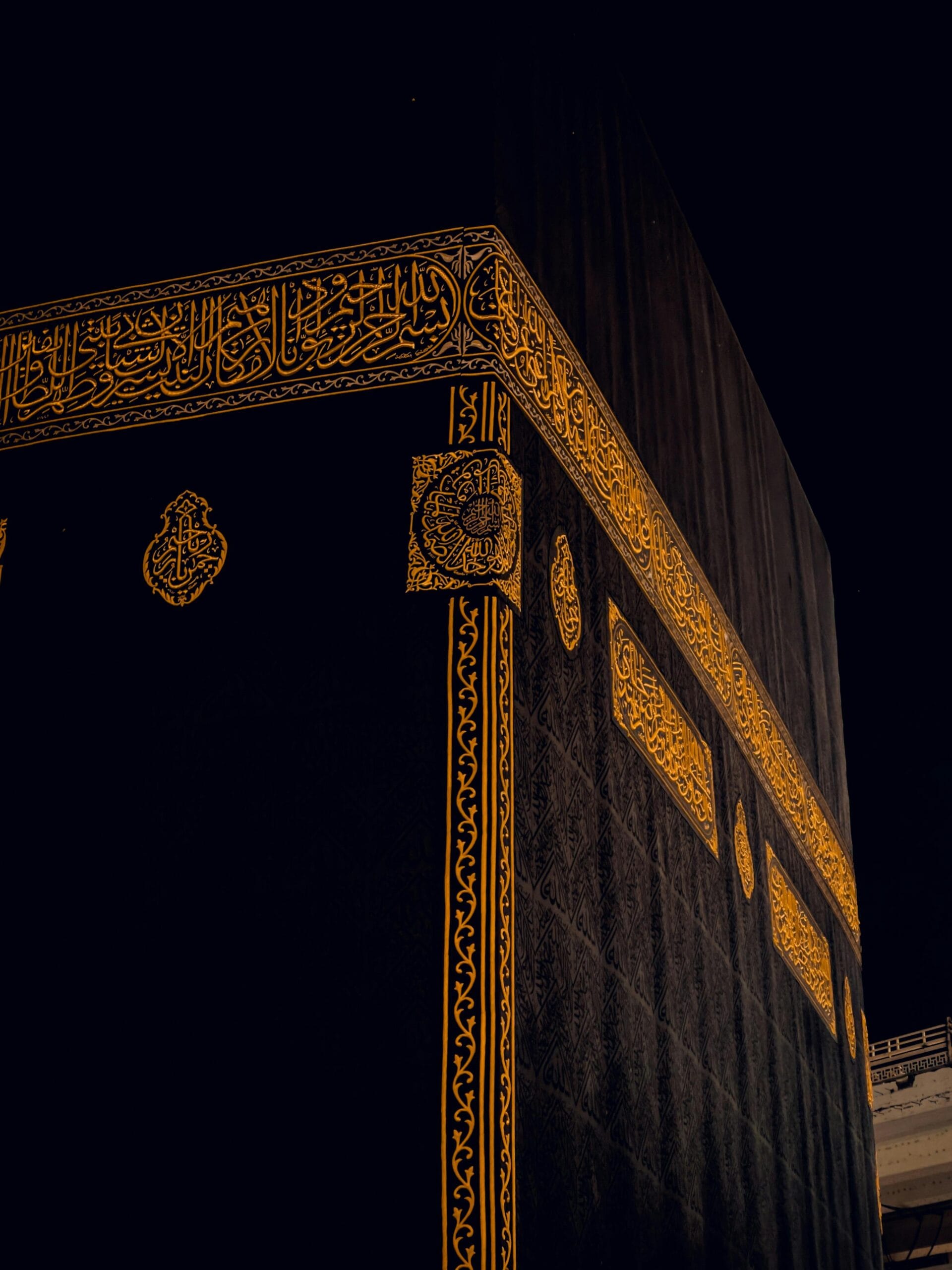 Close-up of the Kaaba in Mecca, Saudi Arabia, showing intricate golden patterns at night.